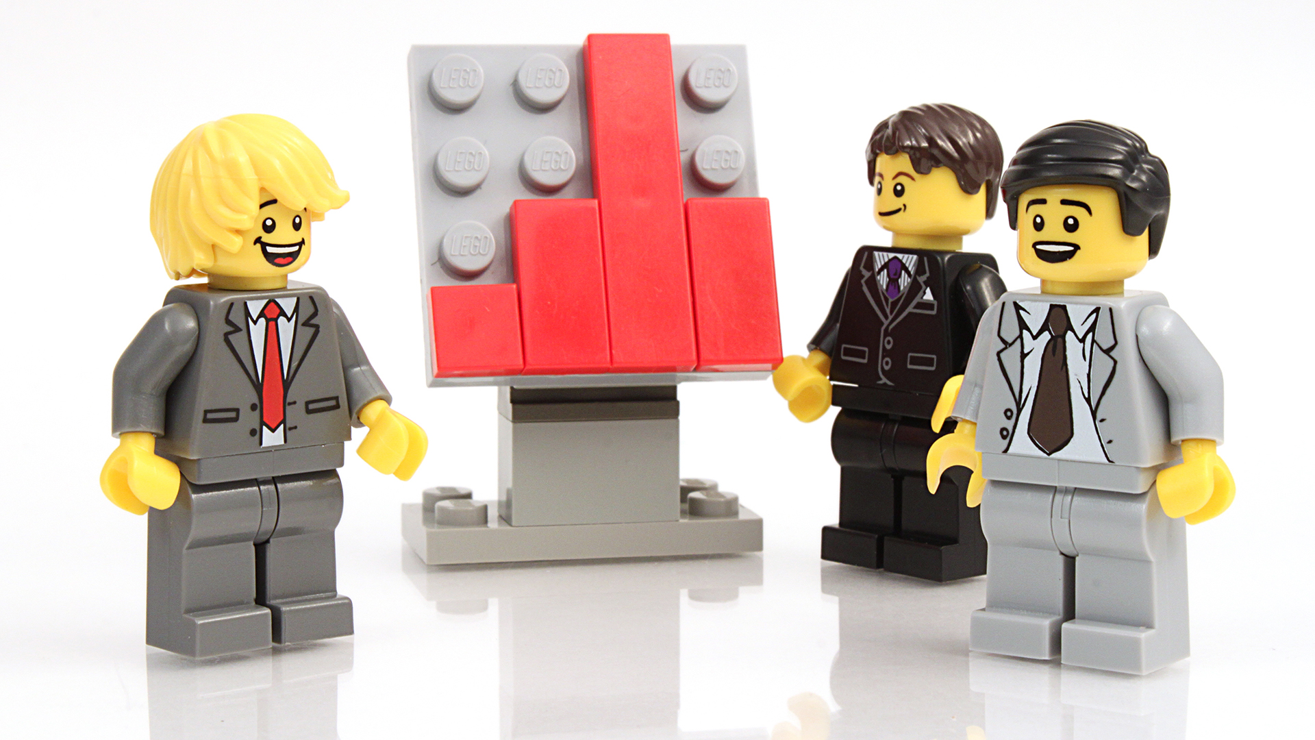 Lego minifigures of office men standing around a chart