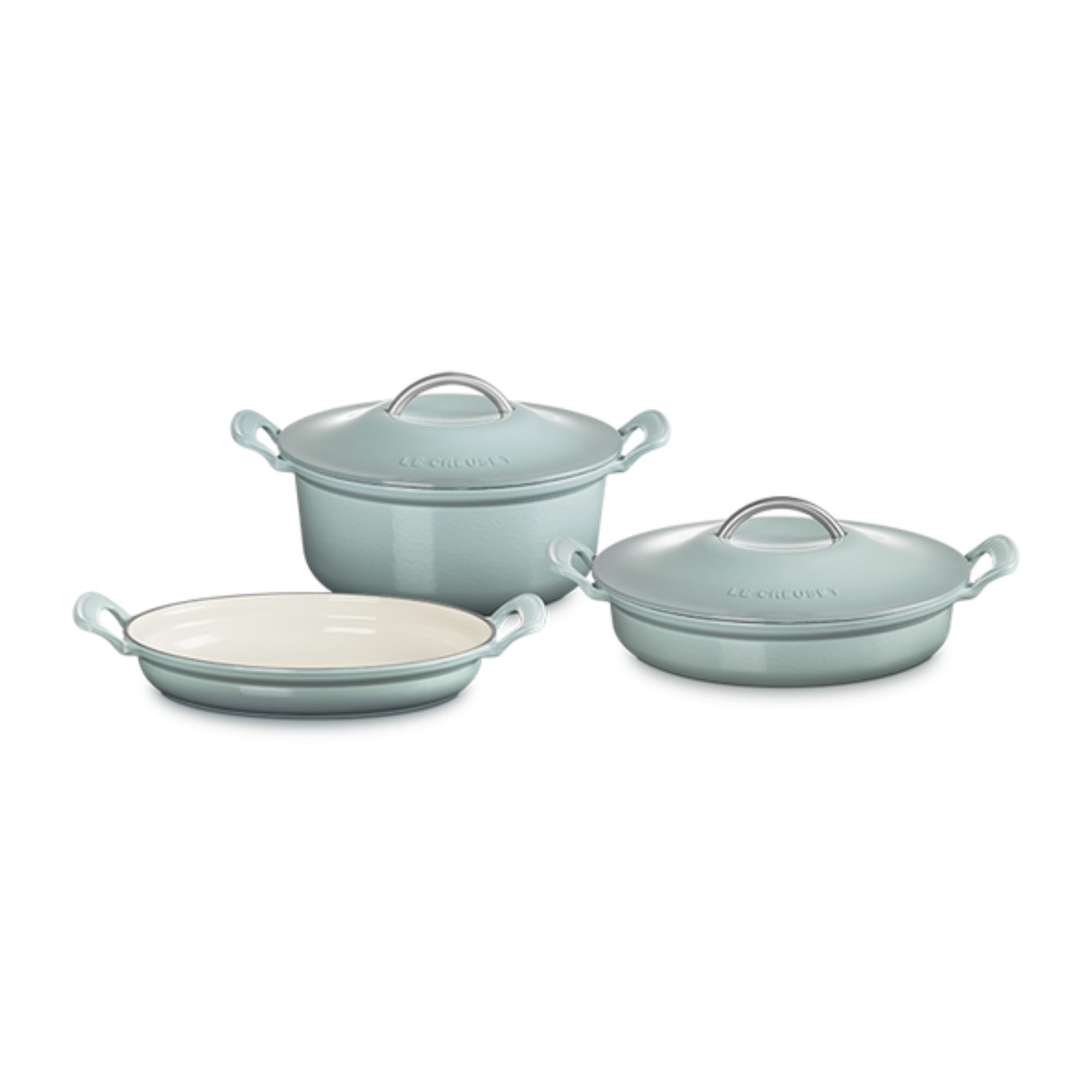 A set of light blue Le Creuset Modern Heritage Round pots, with a Dutch oven, braiser, and low dish, with wide side handles and a curved silver lid handles, against a white background.