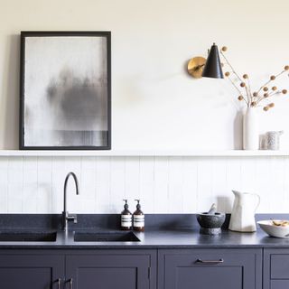 kitchen with black worktop and white wall with shelf and wall light