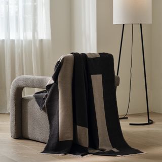 M&S x Kelly Hoppen throw draped over an armchair with a floor lamp next to it