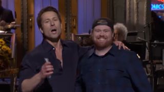 Glen Powell poses with his arm around Mitch from UPS while at SNL.