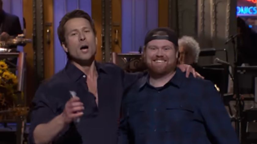 Glen Powell poses with his arm around Mitch from UPS while at SNL.