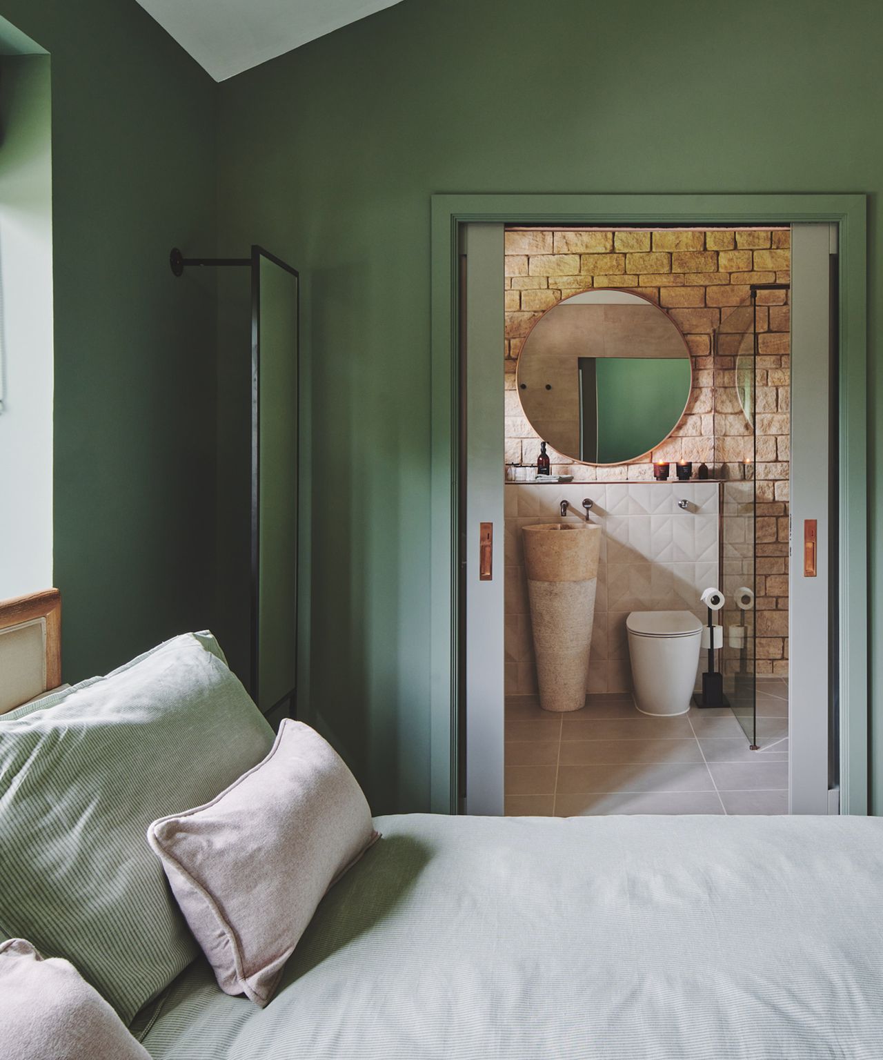 A soft green bedroom looking through to an en suite shower room with sliding doors