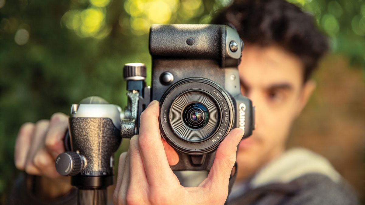 A man focussing the lens attached to a Canon EOS R5 camera outside