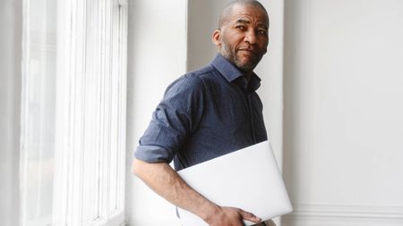 Businessman with laptop standing near window