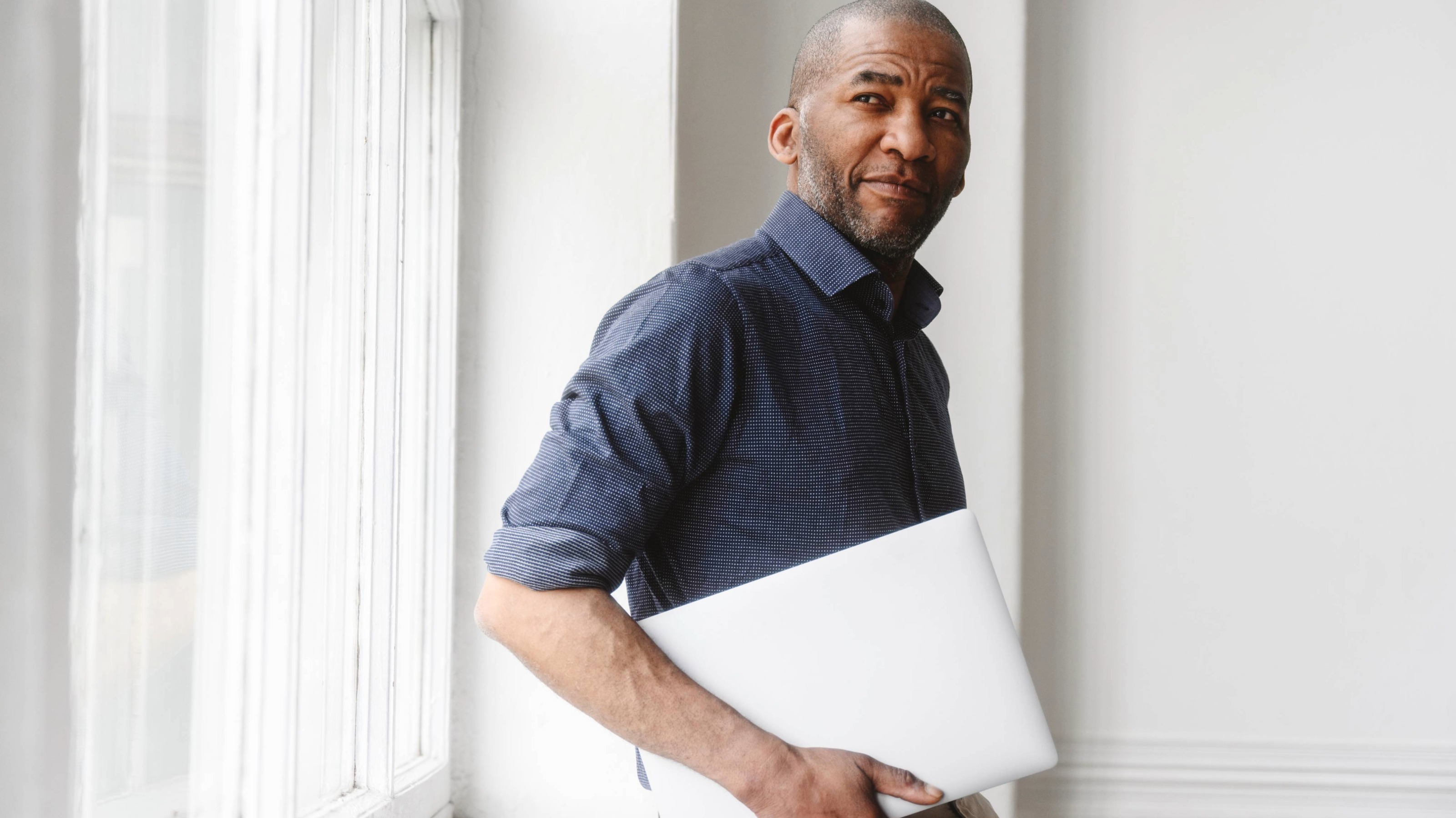 Businessman with laptop standing near window