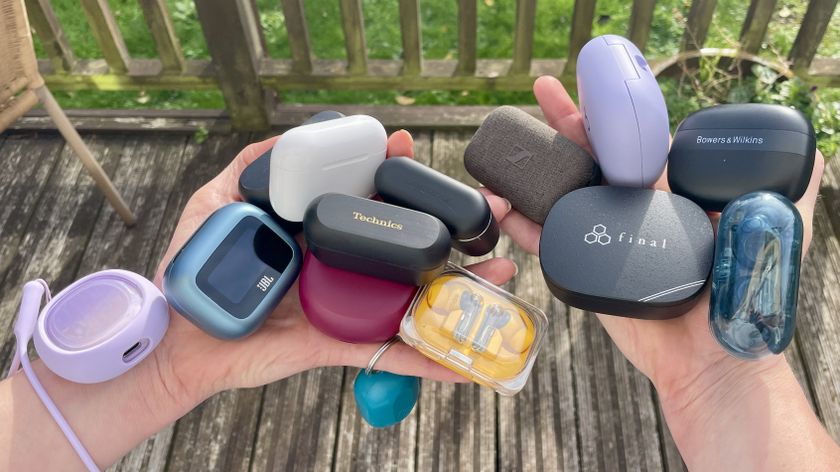 A selection of wireless earbuds, in their cases, held in a woman&#039;s hands on a sunny day