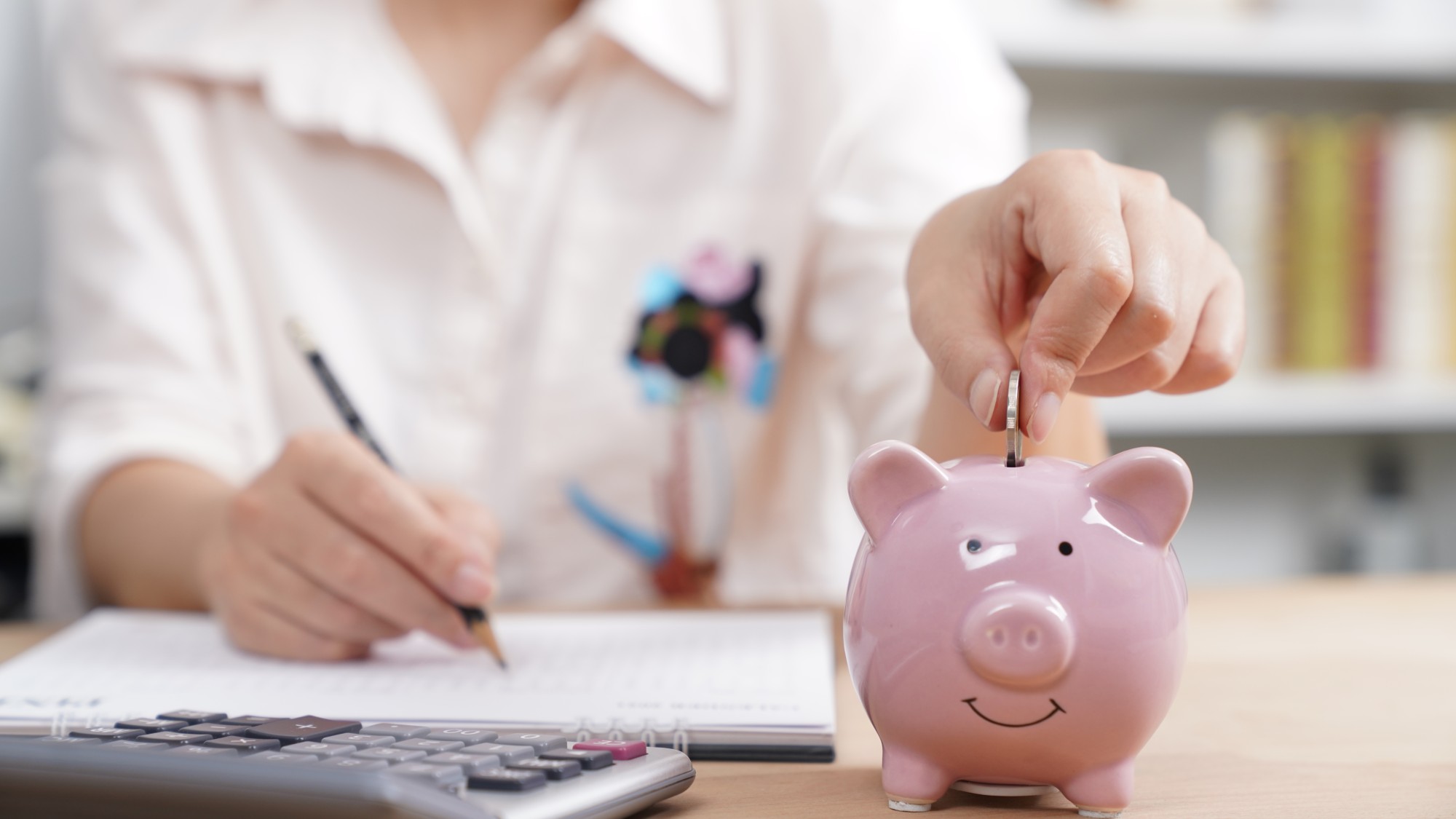 person putting coin in piggy bank