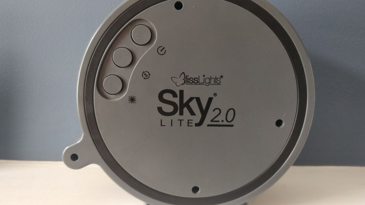 The BlissLights Sky Lite 2.0 star projector sat on a white surface against a blue background