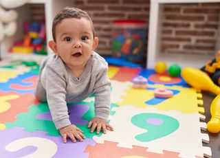 infant child crawling on playmat at nursery