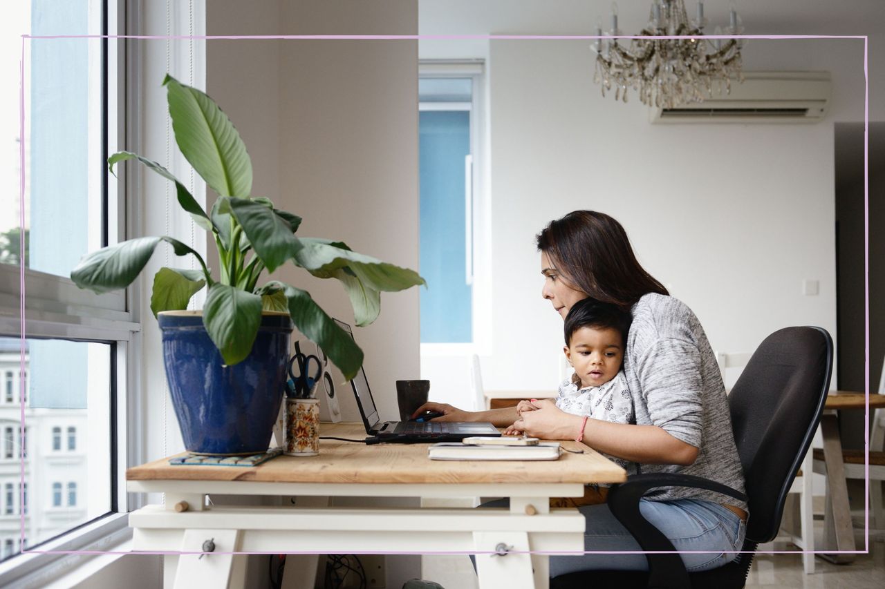 Mother trying to work while young son sits on her lap