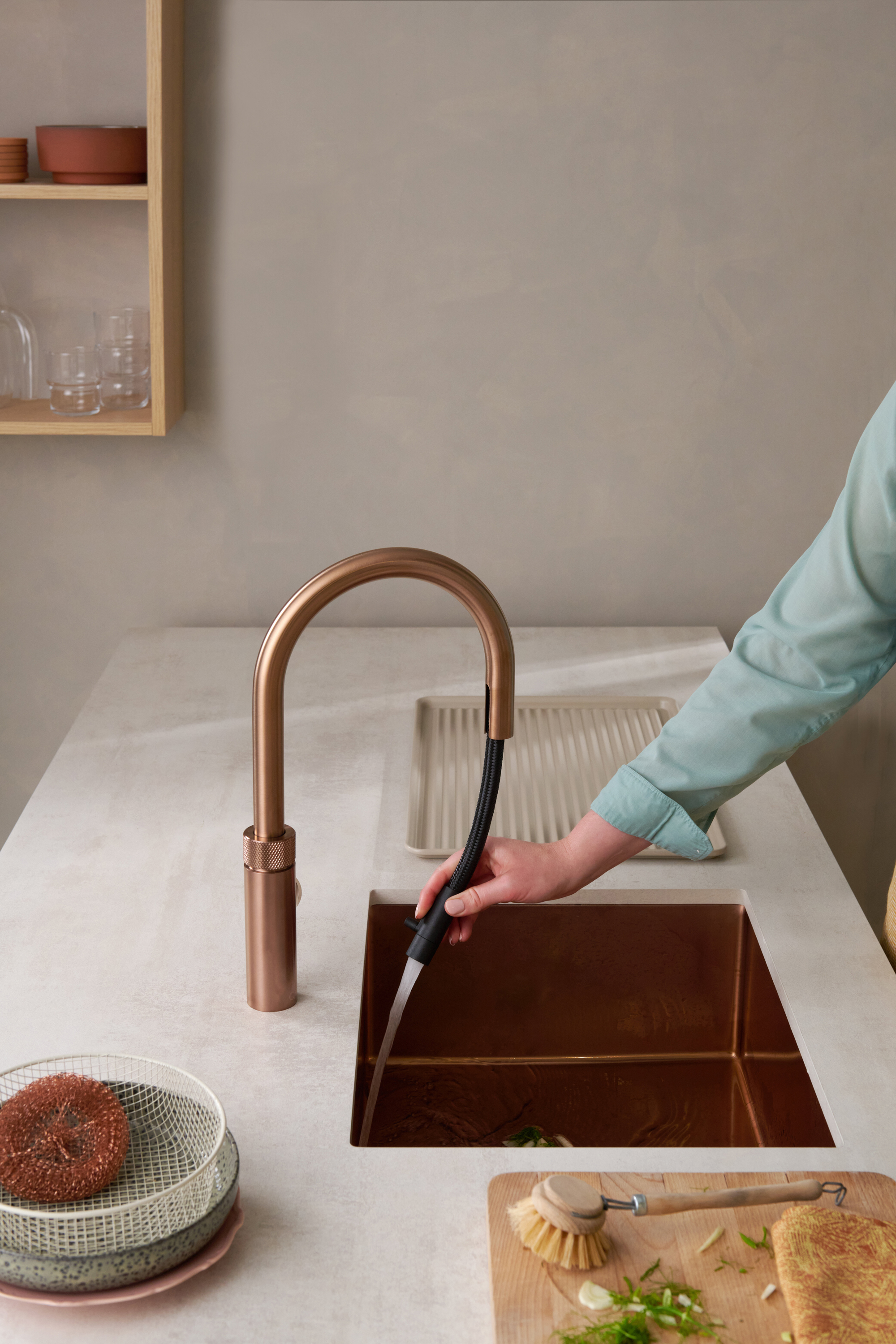 a person pulling out a flex hose from a copper quooker tap