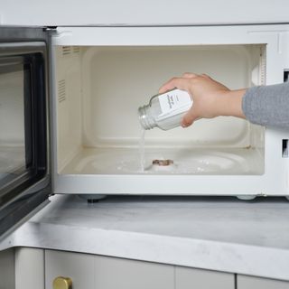 woman's hand sprinkling baking soda in a microwave - phil barker - future