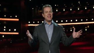The Game Awards 2023 nominee announcements - Geoff Keighley wears a suit jacket and gestures with a smile while standing in an empty theater