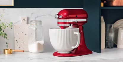 Woman making three layer cake and stand mixer on kitchen counter