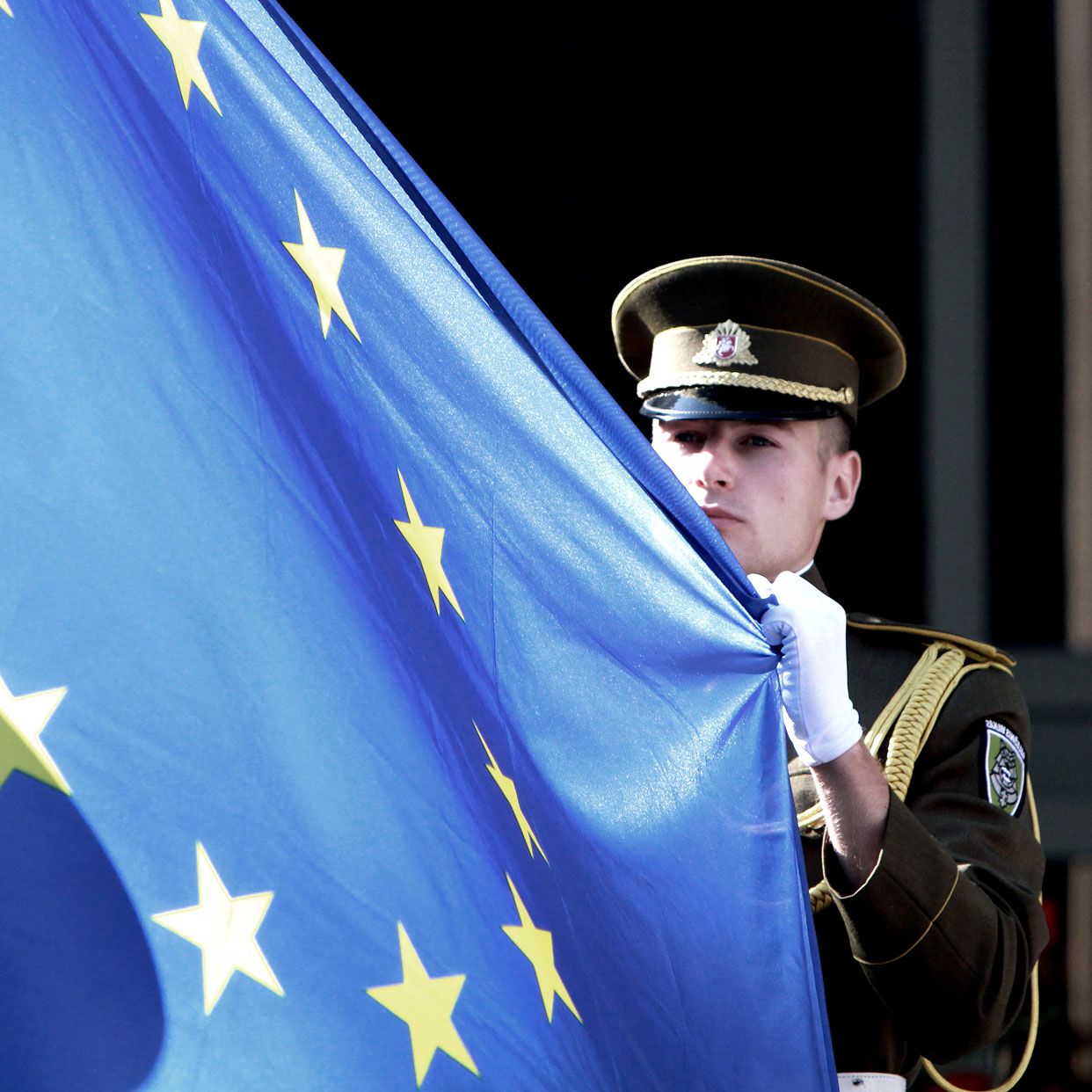 A Lithuanian soldier holds the flag of the European Union during a ceremony in front of the governmental palace in Vilnius on July 1, 2013. The small Baltic nation, the first to break free fr