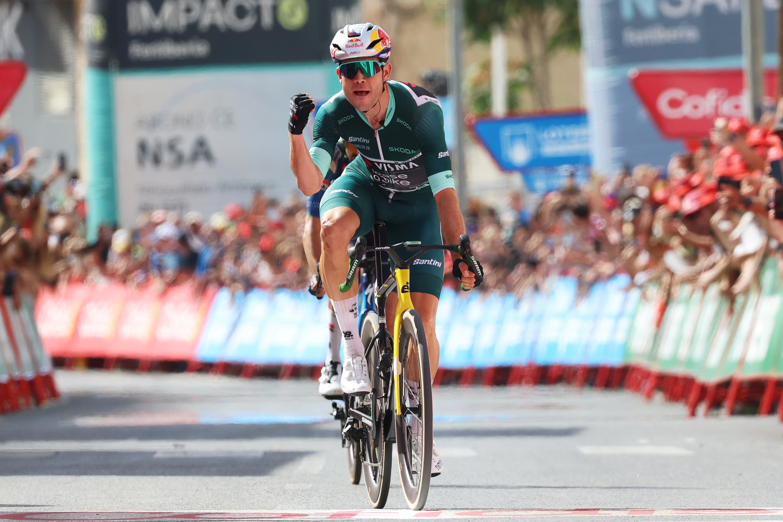 Van Aert flexes with one arm as he crosses the finish line