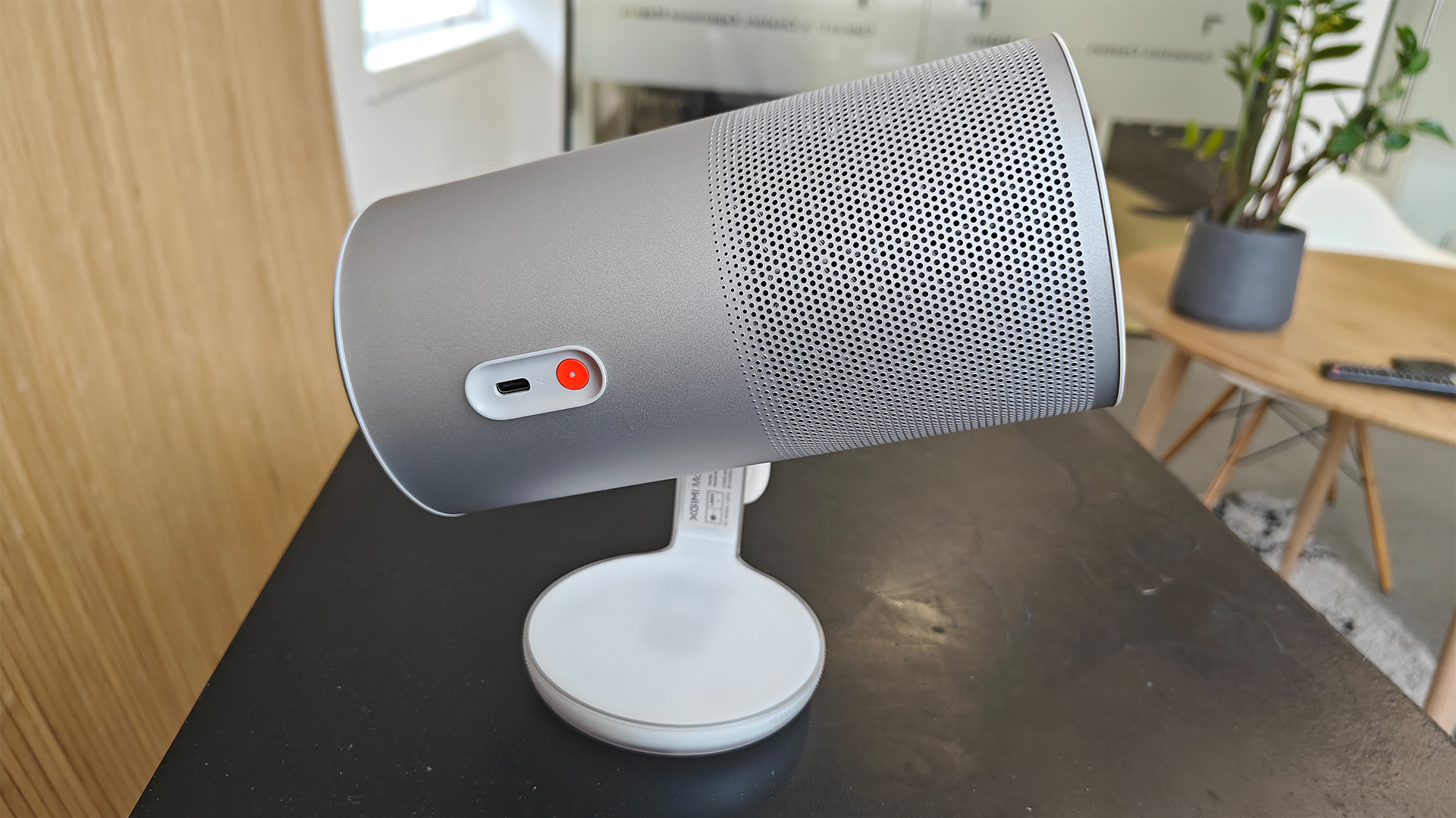 Xgimi MoGo 4 portable projector on black surface against wooden wall side view