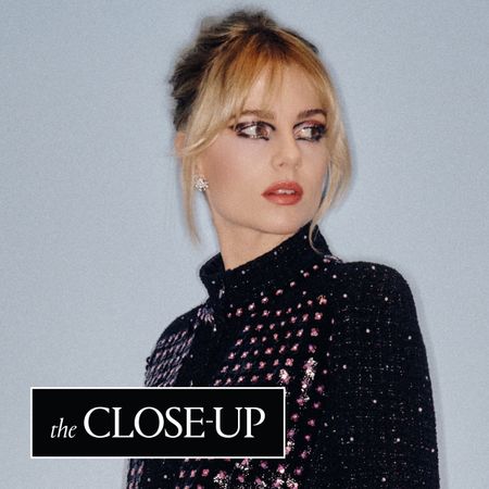 Lucy Boynton in front of a plain wall wearing Chanel