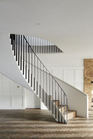 curved white staircase with black railings and wood steps