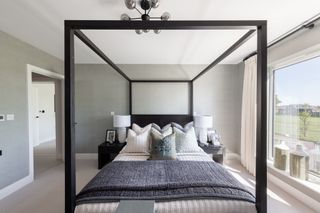 A modern Scandinavian inspired bedroom with a black four poster bed
