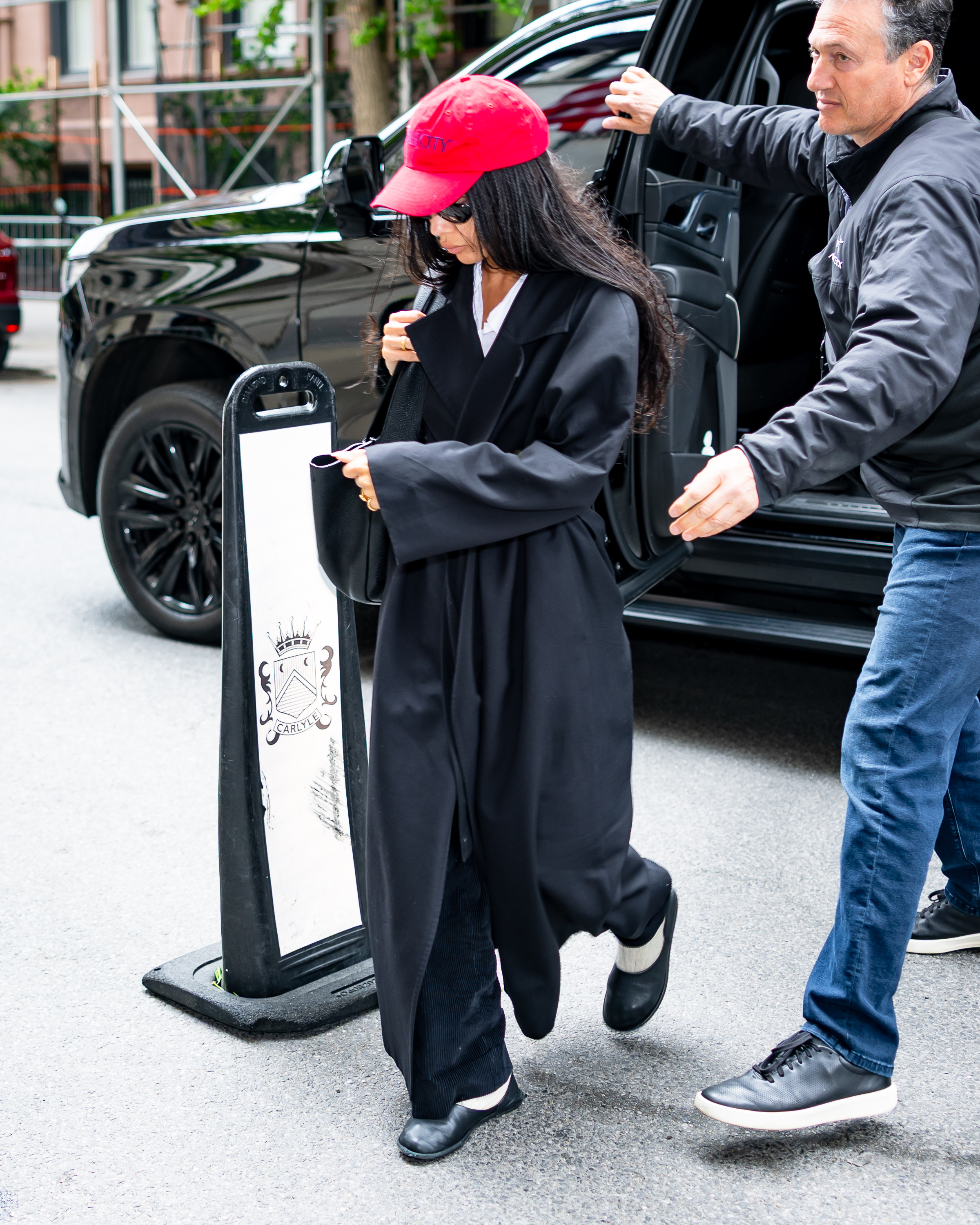 Zoe Kravitz wears leather clogs with a long-line black jacket.
