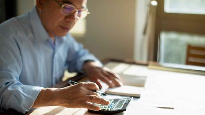 senior man sitting at table and calculating finances