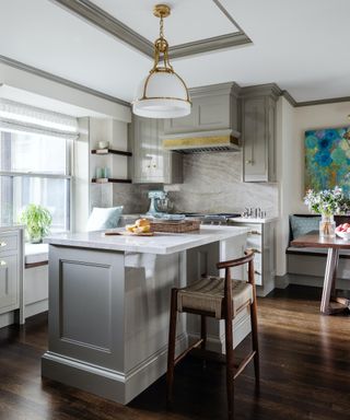 gray kitchen in open plan space with wood stool and window seat