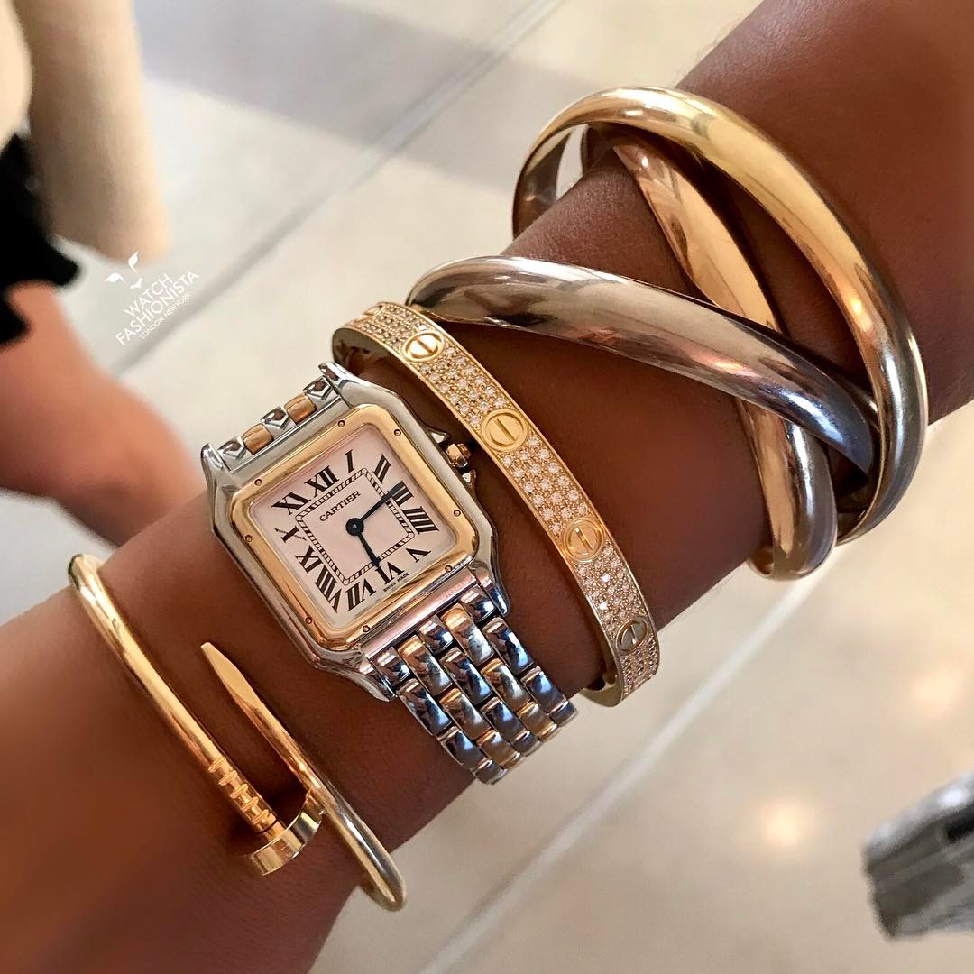 La muñeca de una mujer que muestra su pila de relojes y pulseras.