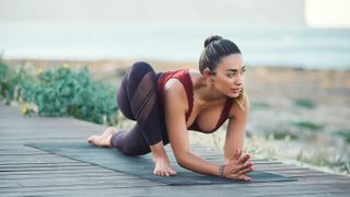 woman making yoga exercises on seaside against blue sea
