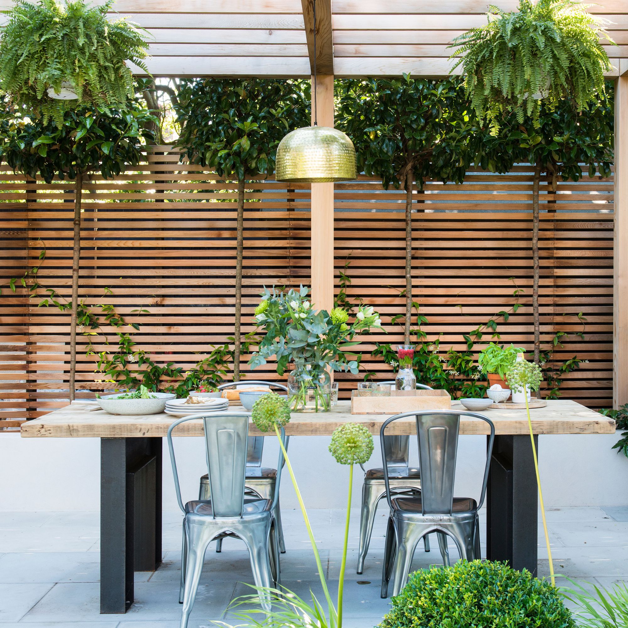 Outdoor seating area with cushions beneath wooden pergola with festoon lights