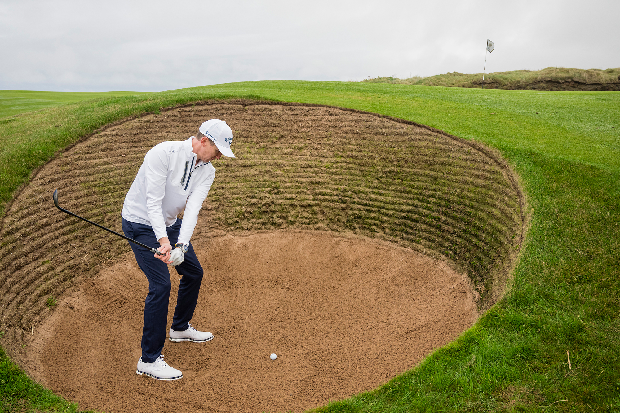 Ben Emerson demonstrating the correct wrist and arm position in the backswing to ensure the club face is open when hitting out of a deep revetted bunker at Trump Turnberry