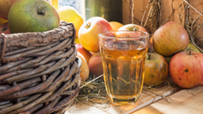 A glass of cider, surrounded by loose apples