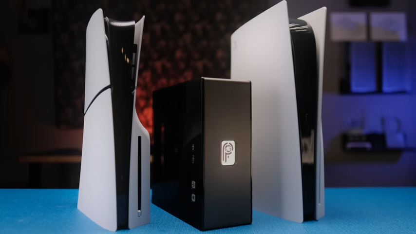 A side-by-side comparison from left to right of the PS5 slim, Not From Concentrate&#039;s tiny PS5 rebuild, and a standard, fullsize PS5 on top of a blue desk.