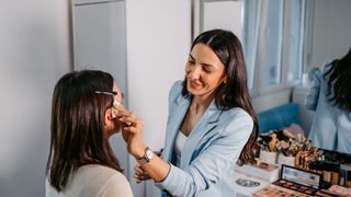 Makeup artist applying makeup to a woman in a chair