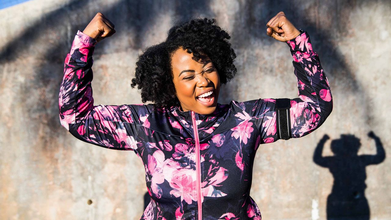 A smiling woman flexes her muscles.