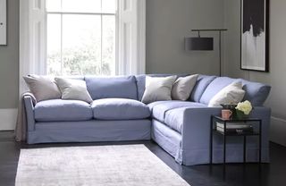 A pale blue corner sofa in a living room with a large window