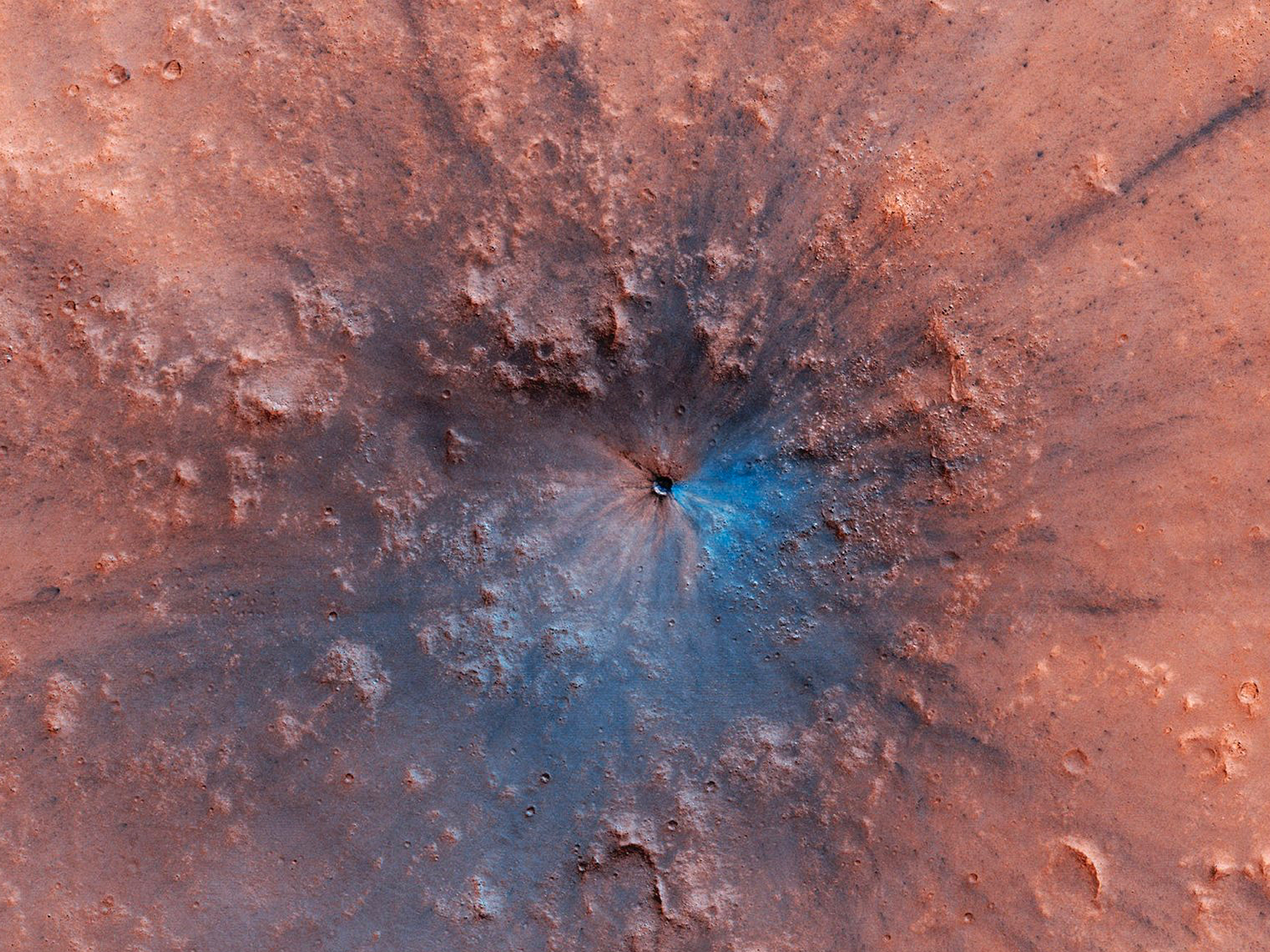 A new crater on Mars, which appeared sometime between September 2016 and February 2019, shows up as a dark smudge on the landscape in this high-resolution photo from the Mars Reconnaissance Orbiter.