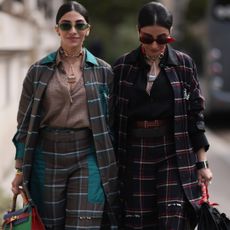 Jyoti Babani (left) and Snehal Babani (right) at fashion week wearing checked suits and sunglasses 