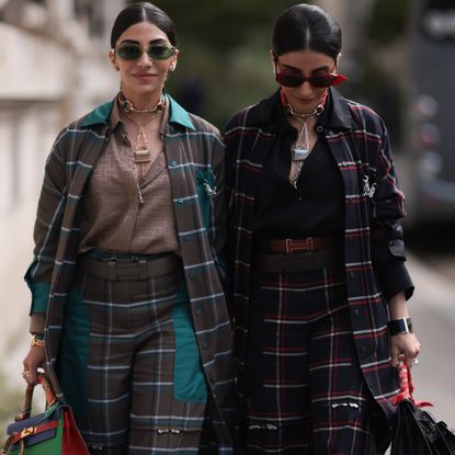 Jyoti Babani (left) and Snehal Babani (right) at fashion week wearing checked suits and sunglasses 