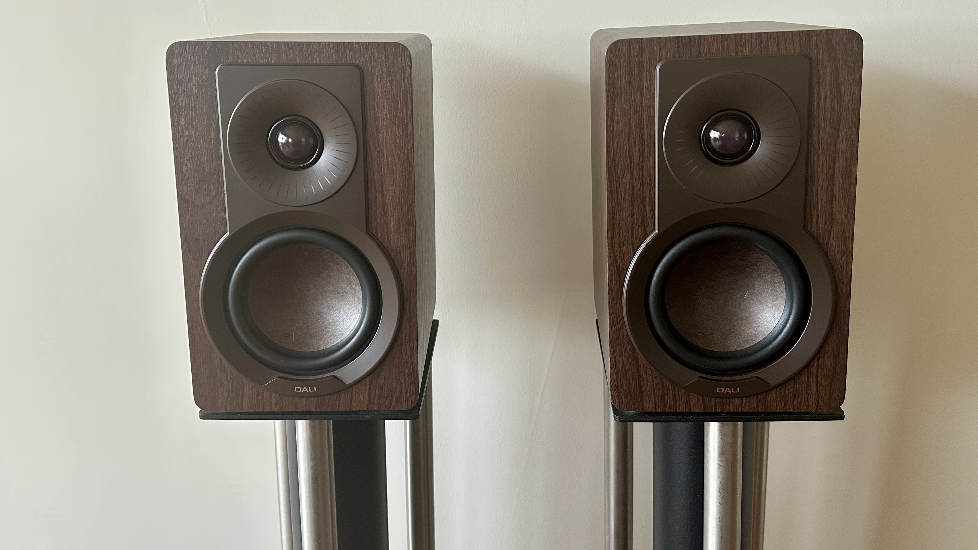 A pair of Dali Kupid bookshelf speakers, each placed on separate speaker stands.