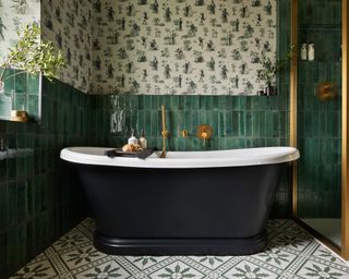 Green bathroom with green tiles, wallpaper, green and white bath, gold finishes, showers, tiled floor