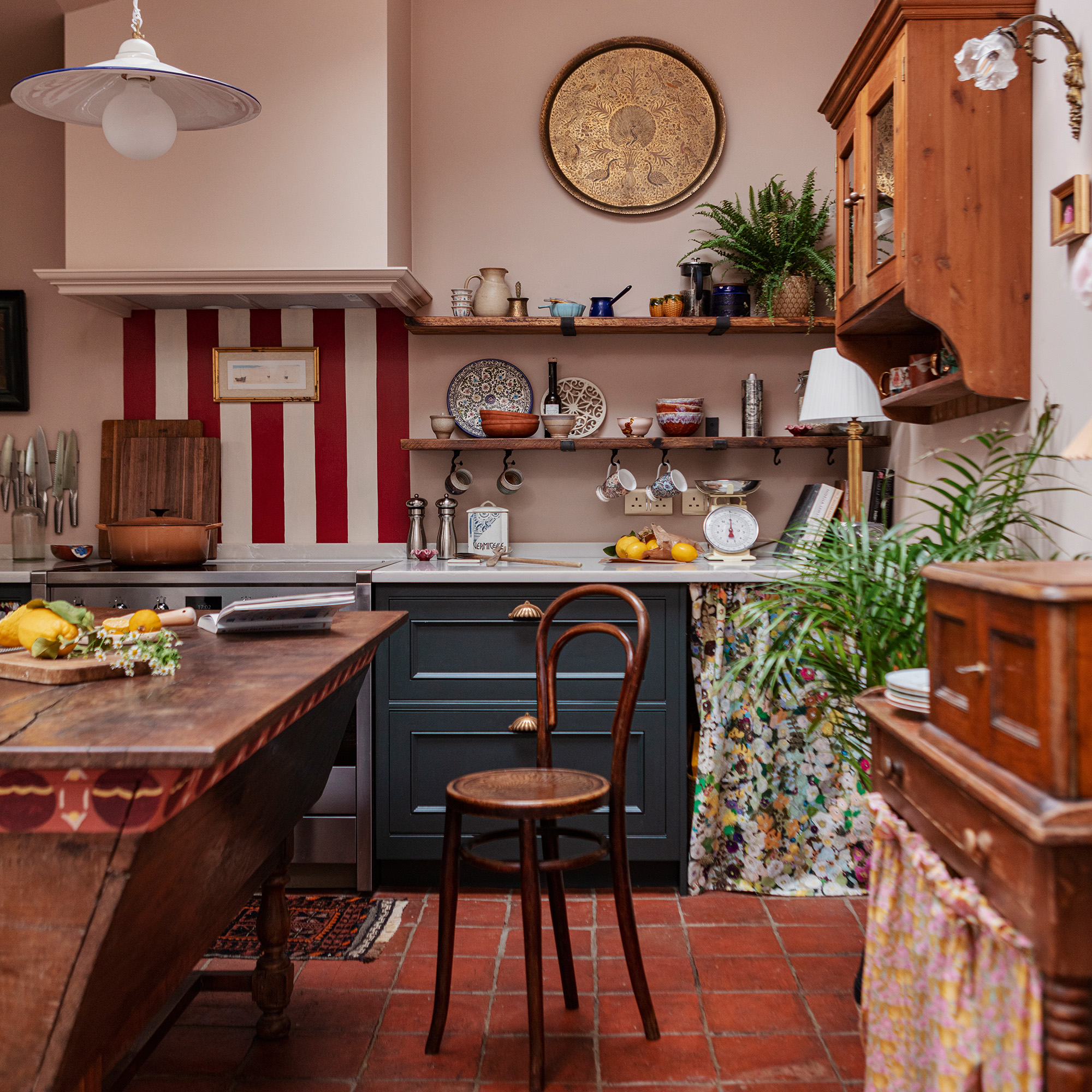 vintage inspired kitchen with red and white splashback blue cabinetry and antique wooden furniture