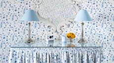 Two blue lamps on table with blue floral wallpaper