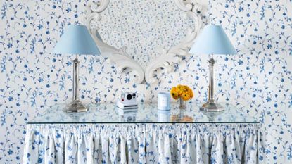 Two blue lamps on table with blue floral wallpaper