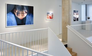 wooden staircase with white railings in art gallery, with a picture of a woman looking down