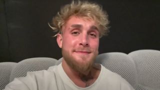 Jake Paul sitting on his couch and smiling.