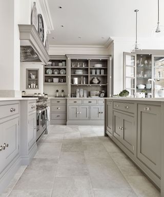 An example of kitchen storage ideas showing a large gray kitchen with cabinets, an island, and open shelving in the background