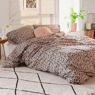 bedroom with white wall and bed with leopard designed cushion and blanket