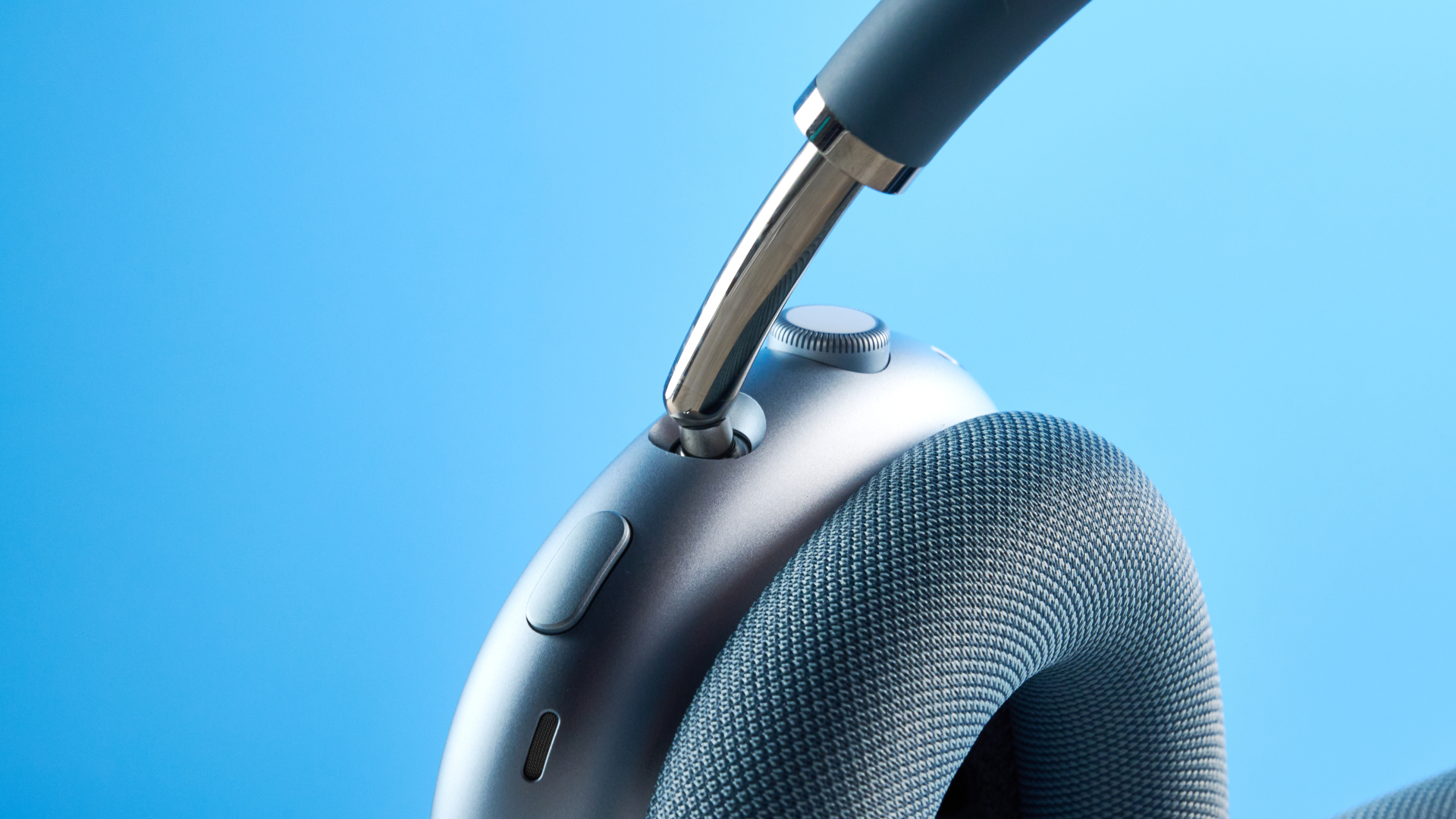 the apple airpods max 2 in blue photographed against a blue tom's guide background, showing the mesh headband, anodized aluminum ear cups, carry case, and controls